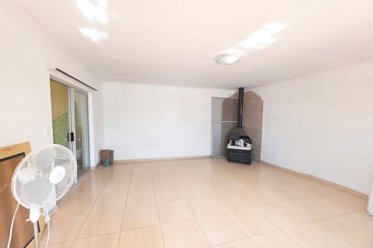 Spacious living area featuring neutral tiled flooring, a built-in fireplace, and sliding glass doors providing access to the exterior.
