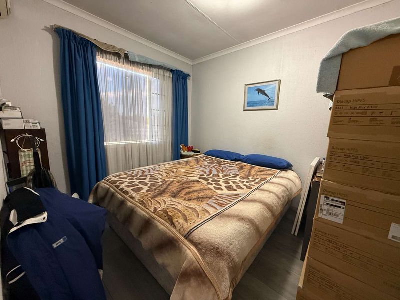 A standard bedroom featuring laminate flooring and a window with curtain rails, providing a functional space for rest.
