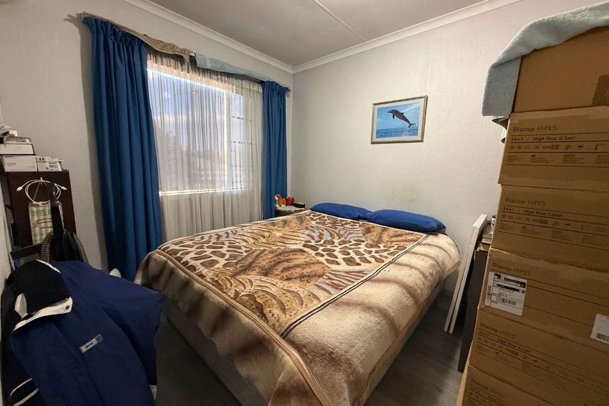 A standard bedroom featuring laminate flooring and a window with curtain rails, providing a functional space for rest.