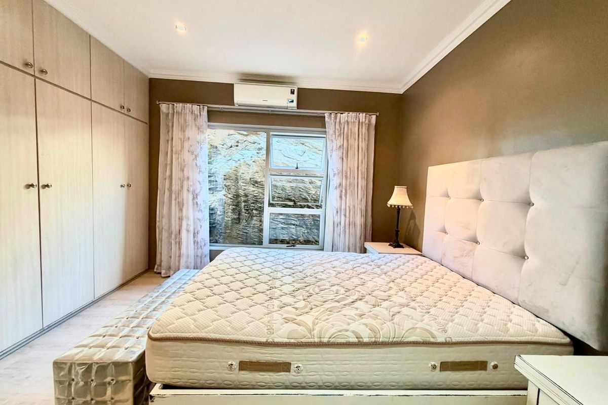 A well-maintained bedroom featuring extensive built-in cabinetry, a split-system air conditioner, and neutral finishes, providing a comfortable and functional living space.