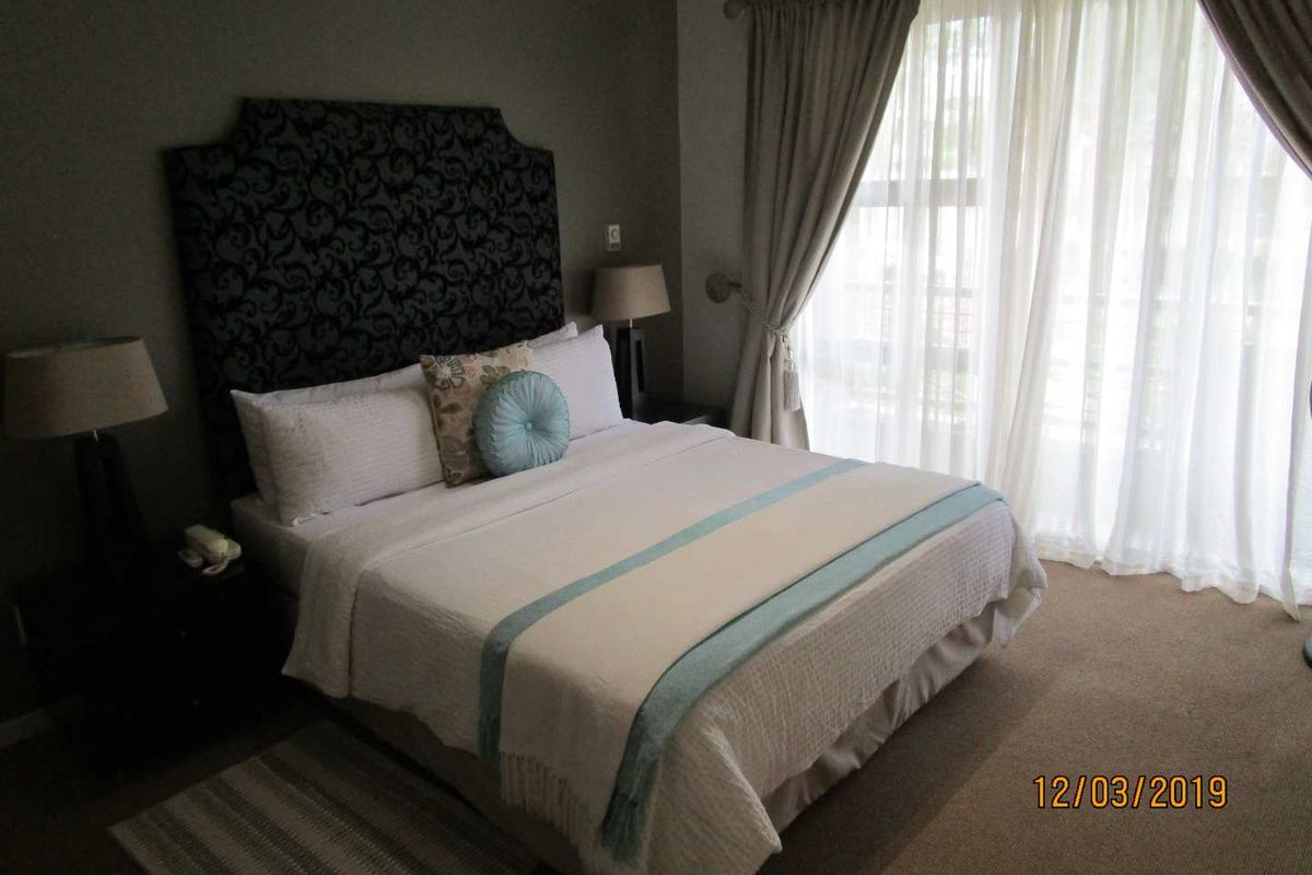 A carpeted bedroom featuring a large sliding glass door with curtains, providing natural light and access to an outdoor area.