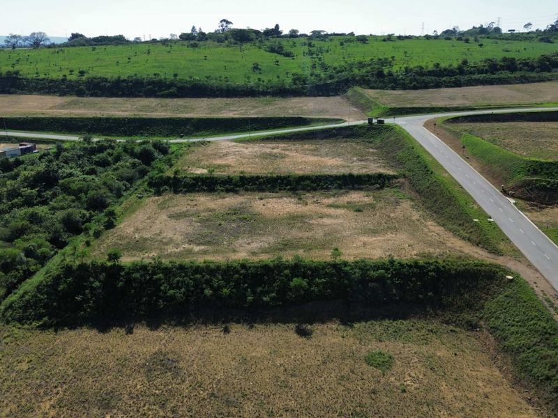 An aerial view of a vacant industrial land plot featuring terraced terrain and adjacent paved road access.