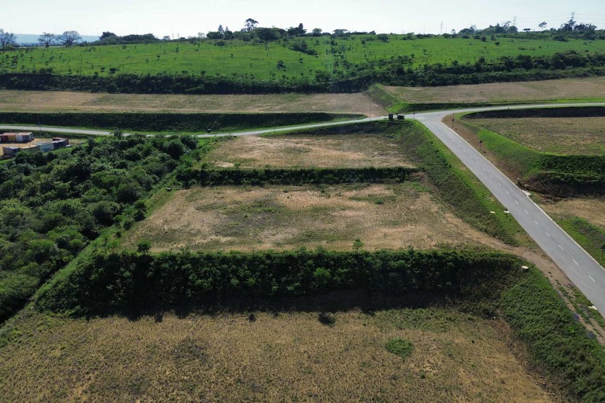 An aerial view of a vacant industrial land plot featuring terraced terrain and adjacent paved road access.