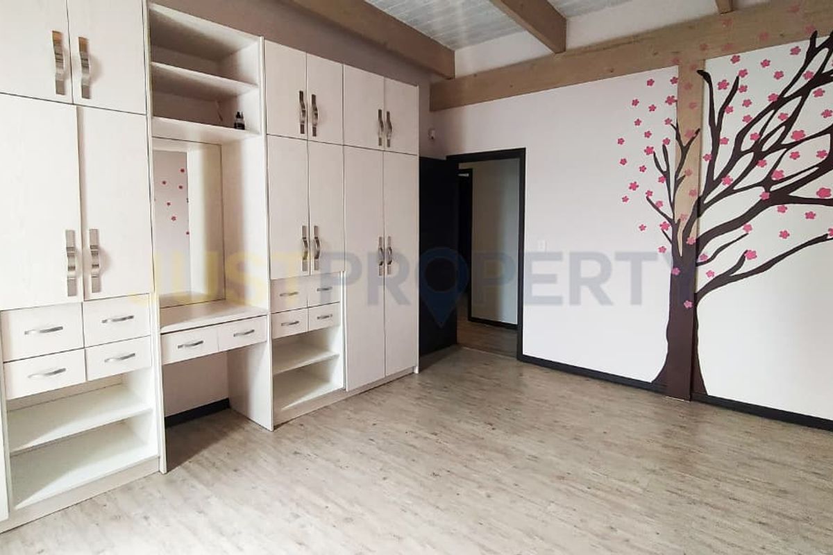 A bedroom featuring extensive built-in cabinetry with integrated vanity and wood-look flooring, accented by a decorative wall mural.