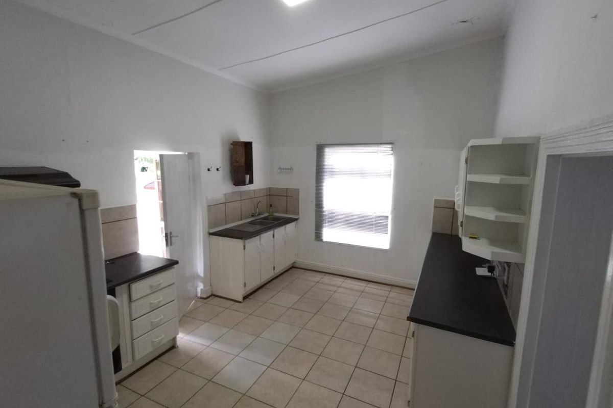 A functional, empty kitchen featuring tiled flooring, built-in cabinetry with dark countertops, and a tiled backsplash, ready for a modern update.