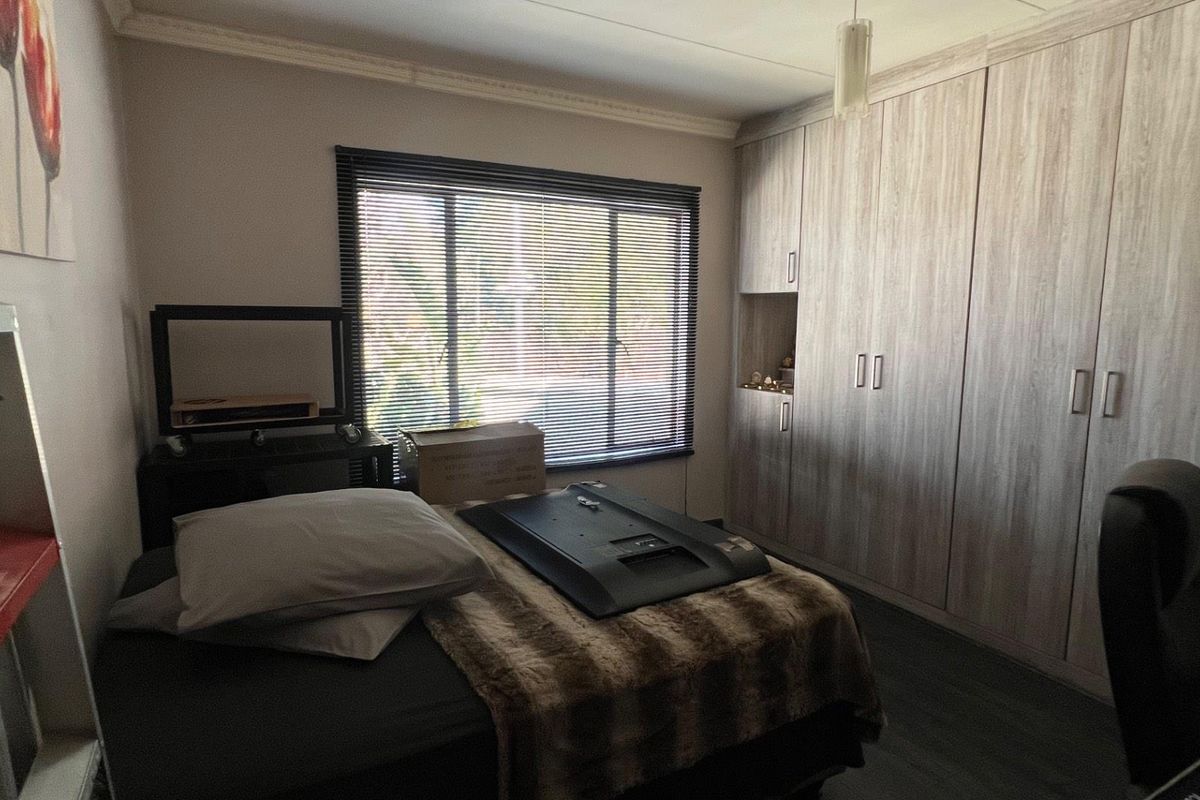 A bedroom featuring extensive built-in wooden cupboards, venetian blinds, and decorative coving, offering practical storage and a neutral foundation.