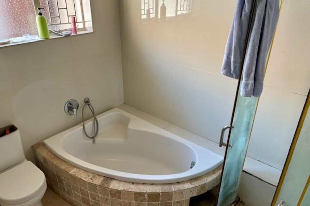 A bathroom featuring a corner bathtub with a tiled surround, a separate shower enclosure, and a standard toilet.