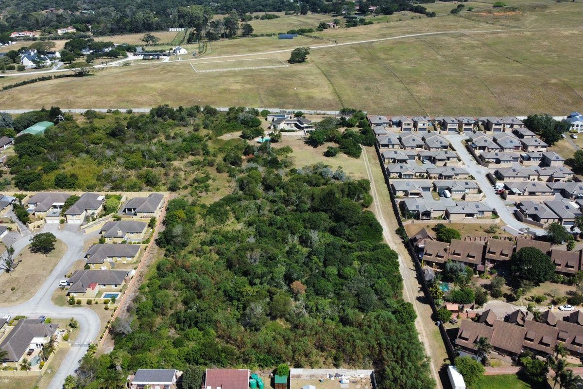 Aerial view of a vacant residential plot surrounded by established housing developments and natural vegetation.