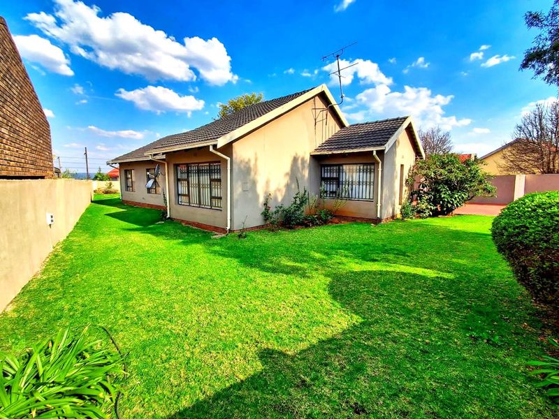 Rear view of the house featuring a tiled roof, security bars on windows, and a well-maintained lawn area.