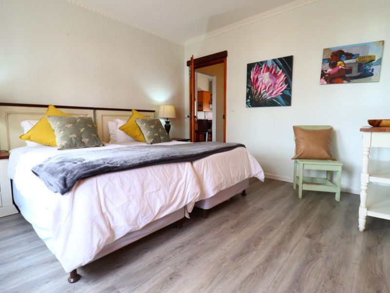 A well-maintained bedroom featuring light-toned laminate flooring, crown molding, and a neutral color palette, offering a comfortable and inviting living space.