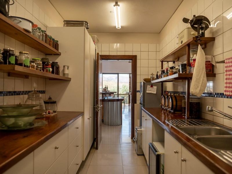 Functional scullery featuring wooden countertops, double stainless steel sink, tiled splashbacks, and ample built-in cabinetry with open shelving for organized storage.