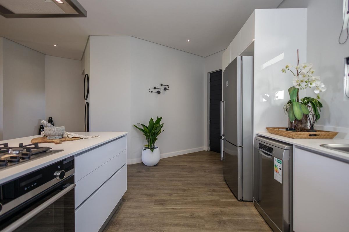 Modern kitchen featuring sleek white cabinetry, integrated appliances, a gas cooktop, and durable wood-look flooring in a clean, contemporary layout.