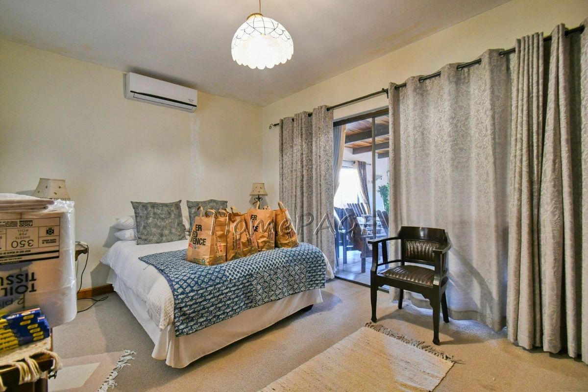 A bedroom featuring a wall-mounted air conditioning unit and sliding glass doors providing access to an outdoor patio area.