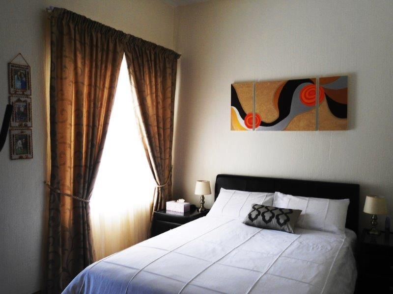 A cozy bedroom featuring a window with curtains and neutral wall finishes.