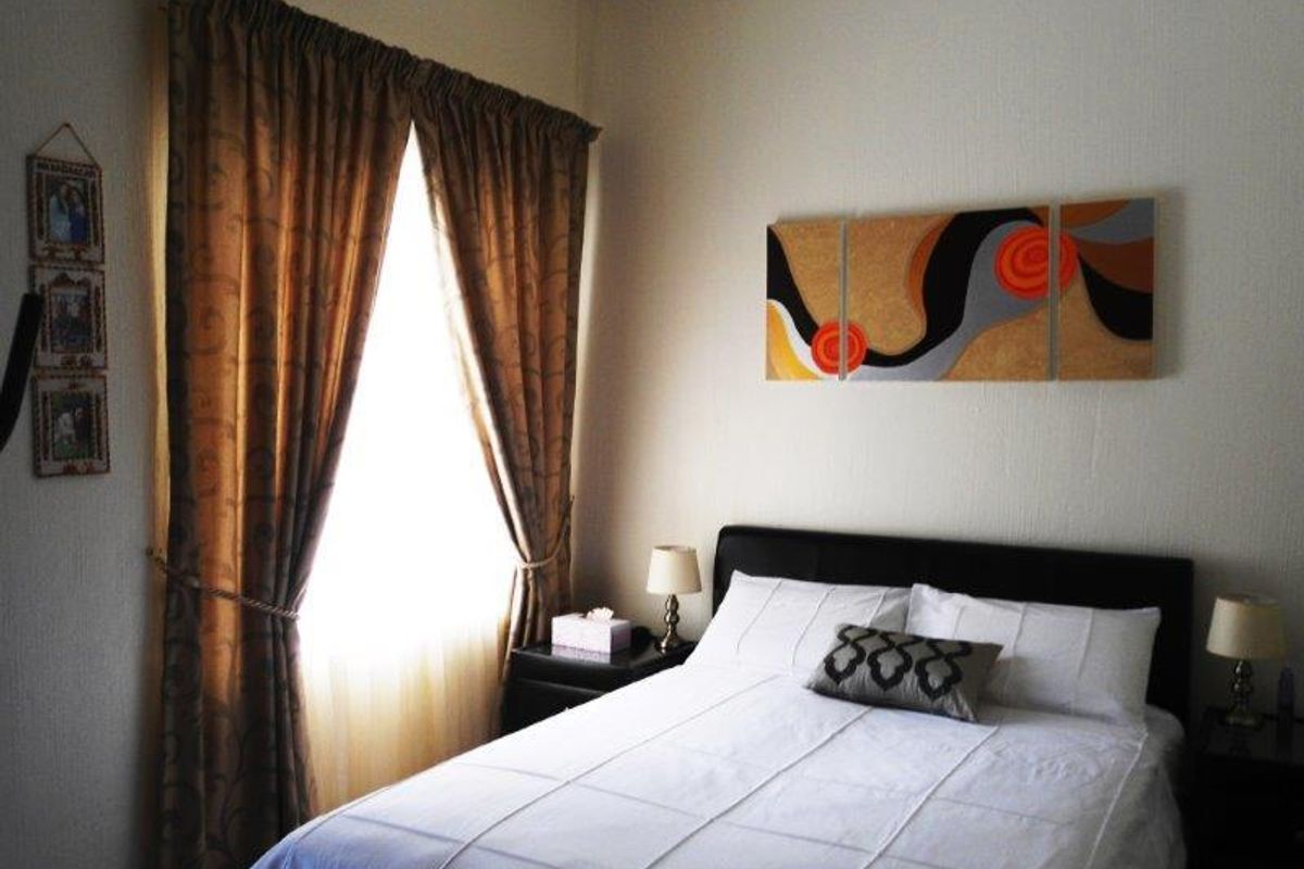A cozy bedroom featuring a window with curtains and neutral wall finishes.