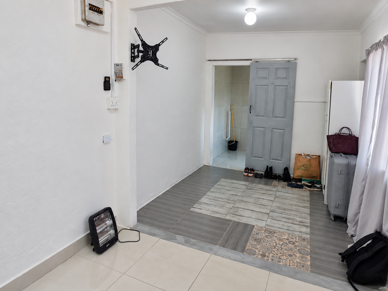 An entry area featuring tiled flooring, a wall-mounted TV bracket, and a sliding door leading to an adjacent space.