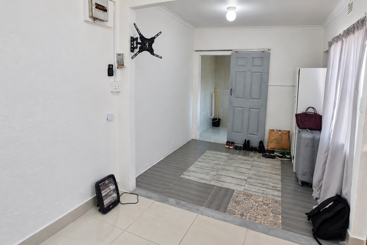 An entry area featuring tiled flooring, a wall-mounted TV bracket, and a sliding door leading to an adjacent space.