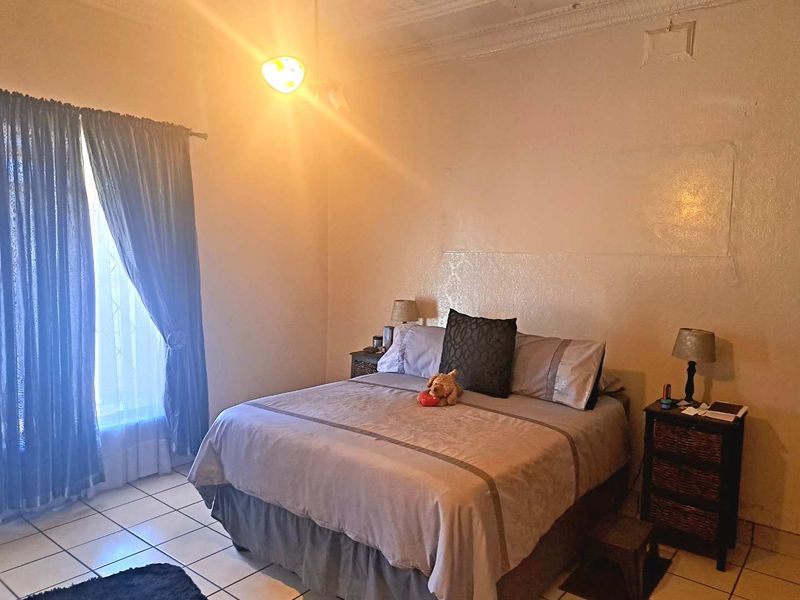 A bedroom featuring tiled flooring, decorative ceiling cornice, and a ceiling rose, requiring cosmetic updates to the wall finishes.