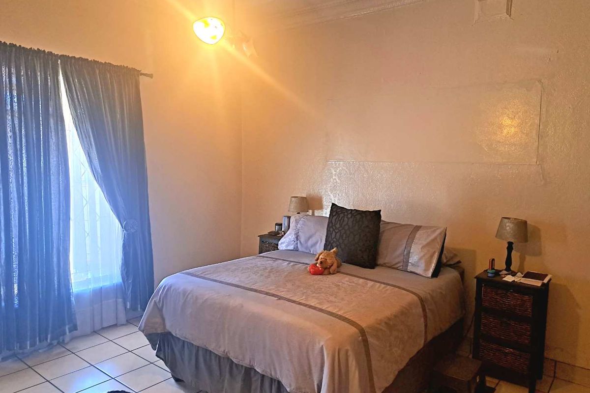 A bedroom featuring tiled flooring, decorative ceiling cornice, and a ceiling rose, requiring cosmetic updates to the wall finishes.