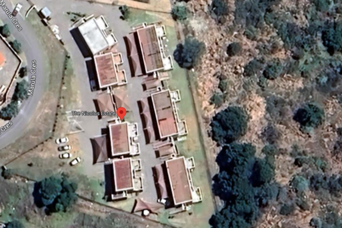 Aerial view of The Nicolus Estate apartment complex, showing the layout of the buildings, parking areas, and surrounding landscape.