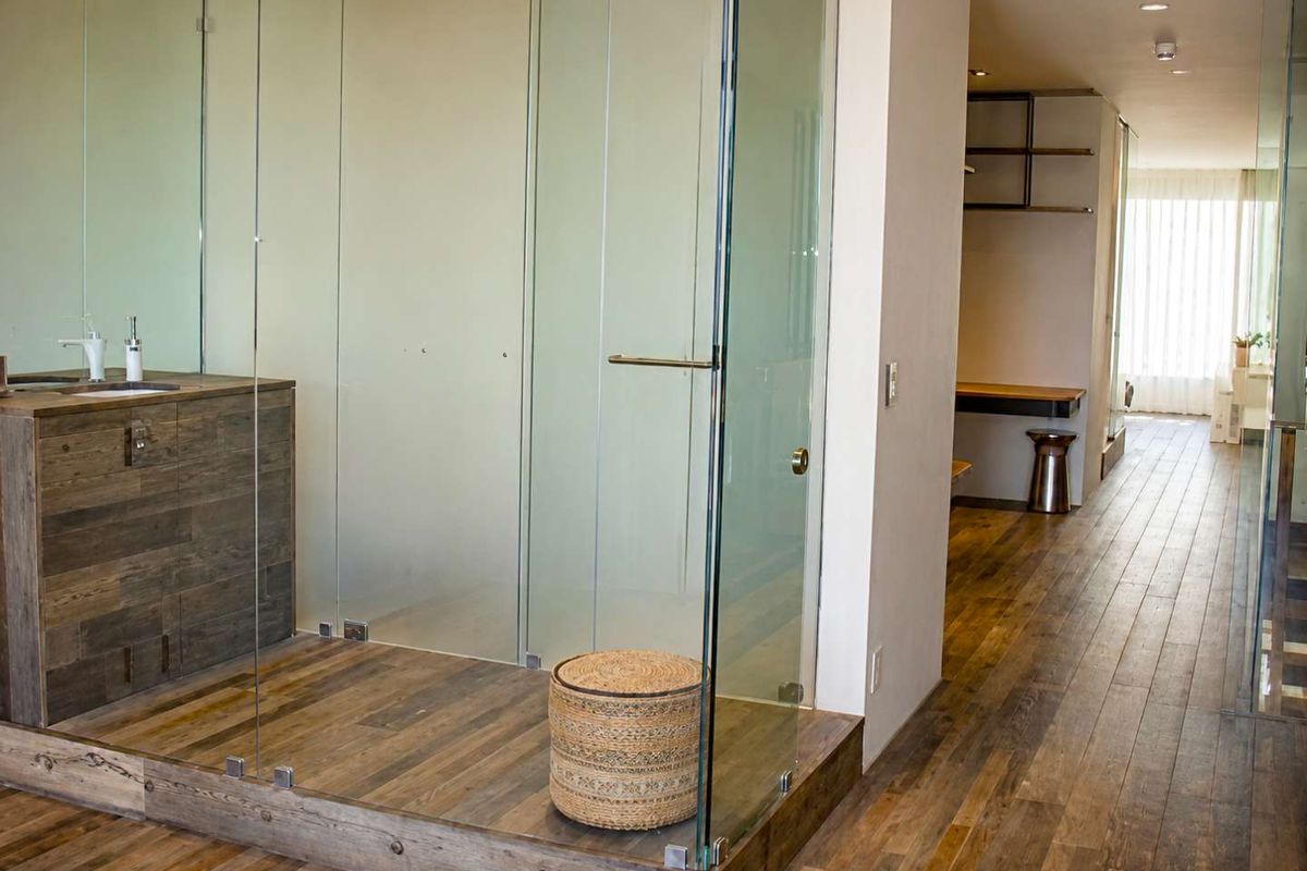 Modern bathroom featuring a glass-enclosed shower, timber vanity with integrated basin, and warm timber flooring, creating a sleek and contemporary aesthetic.