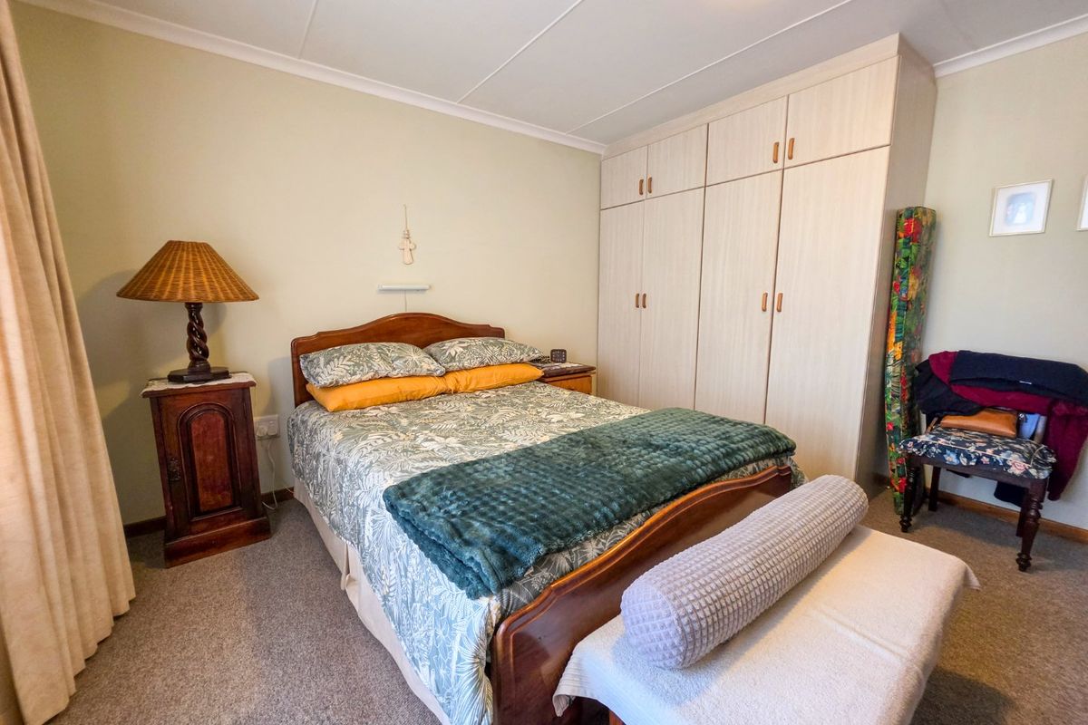 A functional bedroom featuring neutral walls, carpeted flooring, and ample built-in cupboard storage space.