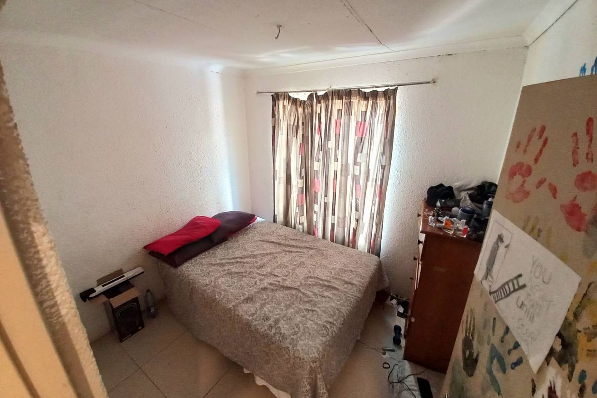 A compact bedroom featuring tiled flooring and a window with curtain rails, offering a functional space for rest.