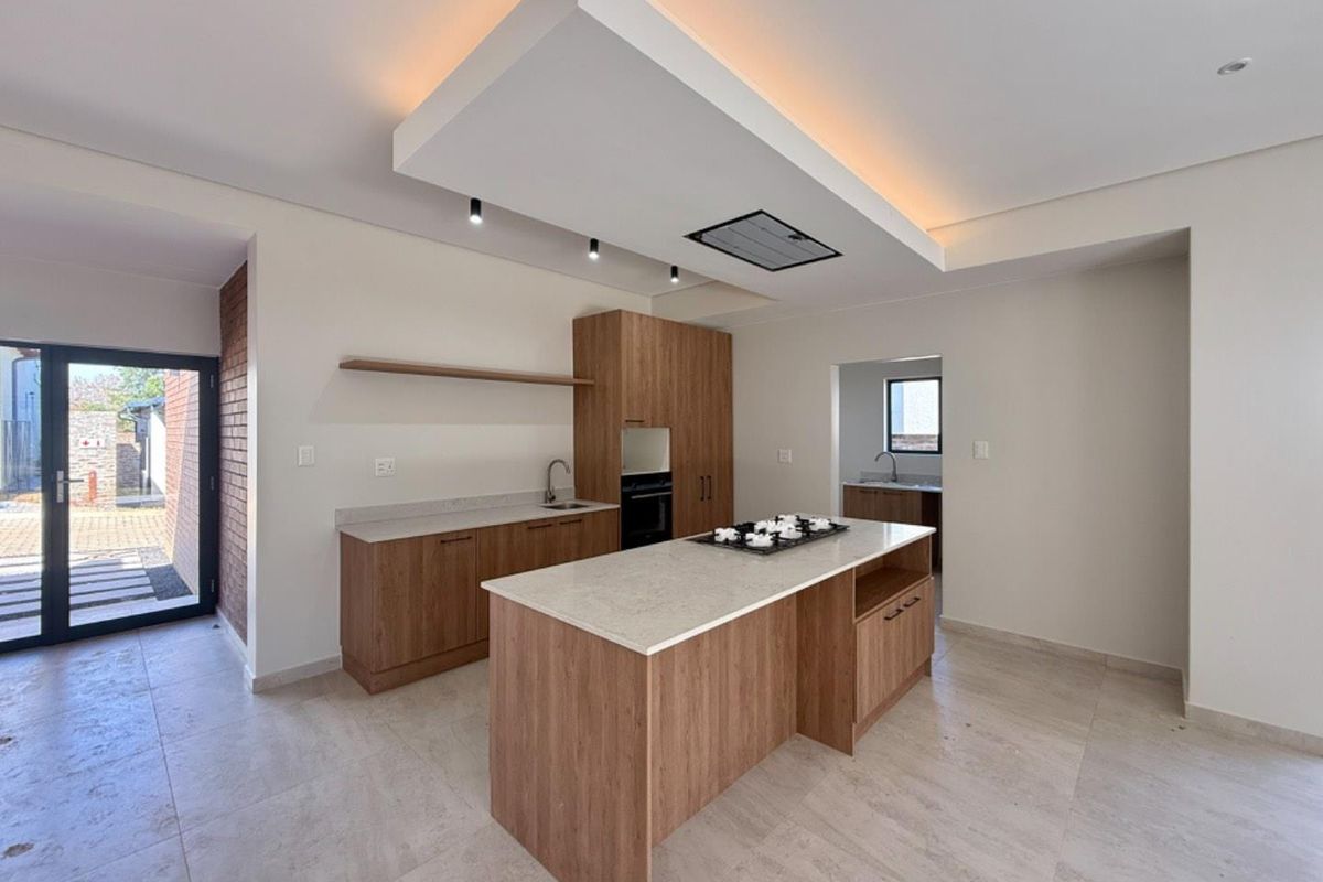 Modern kitchen featuring a central island with gas hob, built-in oven, stone countertops, and a stylish drop ceiling with integrated lighting.