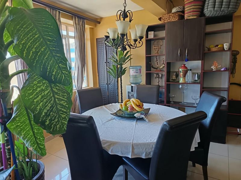A dining room featuring a built-in shelving unit, a decorative chandelier, and tiled flooring, providing a functional space for meals.