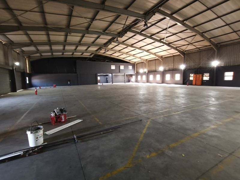 Spacious industrial warehouse featuring high ceilings, concrete flooring, and a mezzanine level, suitable for storage, manufacturing, or distribution operations.