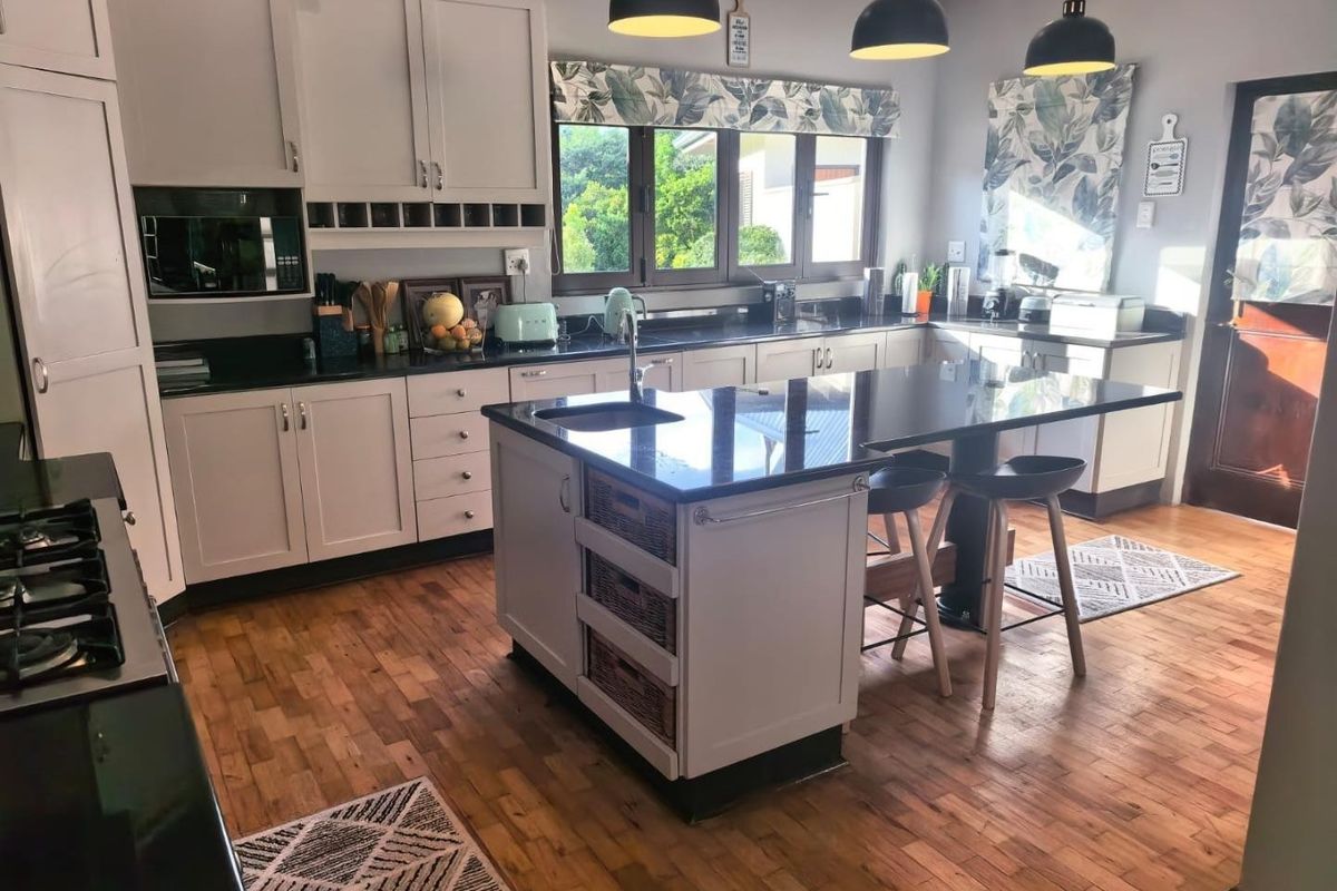 A well-appointed kitchen featuring a central island with stone countertops, ample cabinetry, gas hob, and warm hardwood flooring.