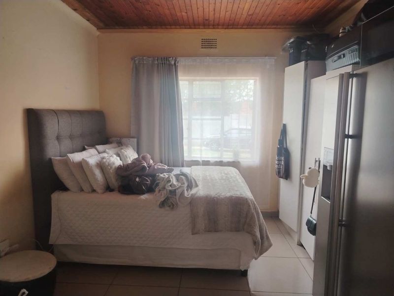A bedroom featuring a timber ceiling, tiled flooring, and a built-in cupboard, providing a functional living space.