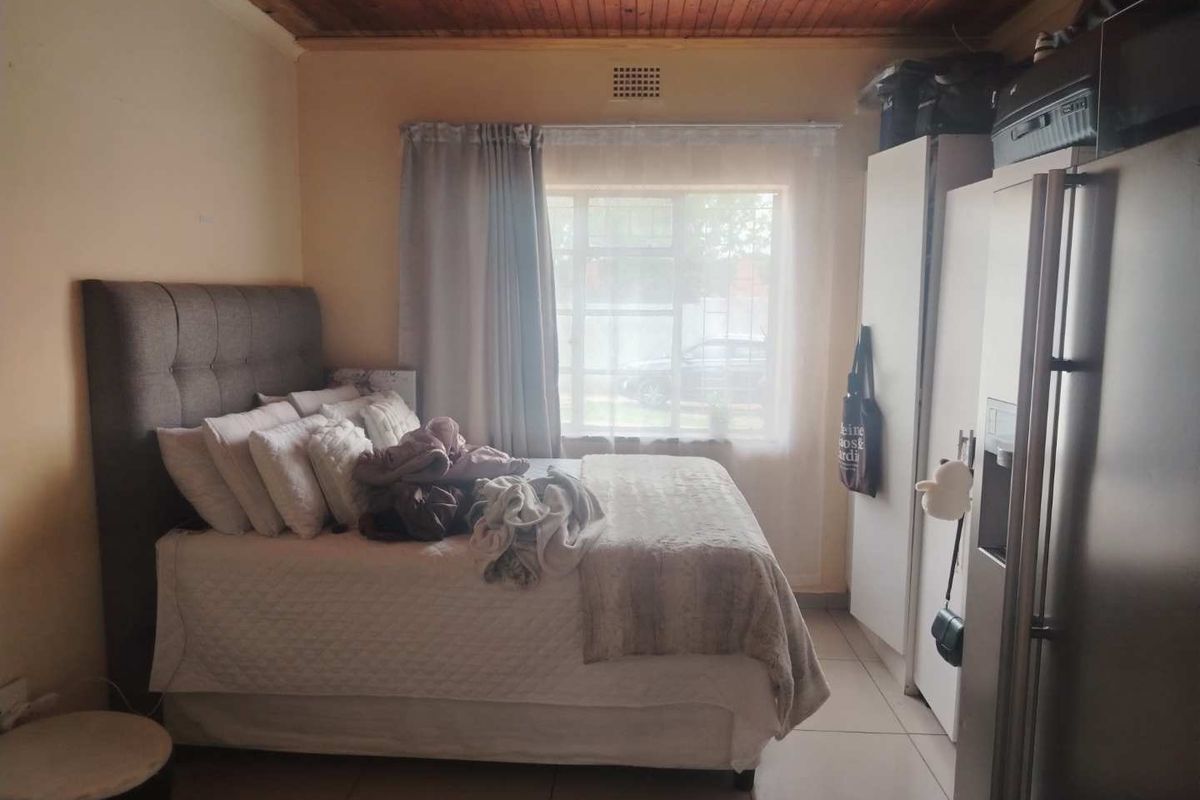 A bedroom featuring a timber ceiling, tiled flooring, and a built-in cupboard, providing a functional living space.