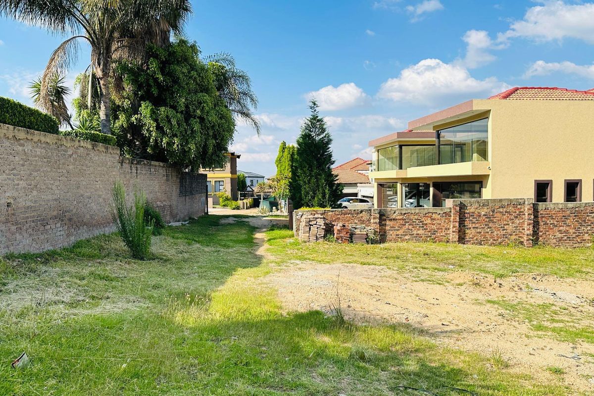A vacant residential plot featuring perimeter brick boundary walls and established greenery, situated in a developed suburban neighborhood.