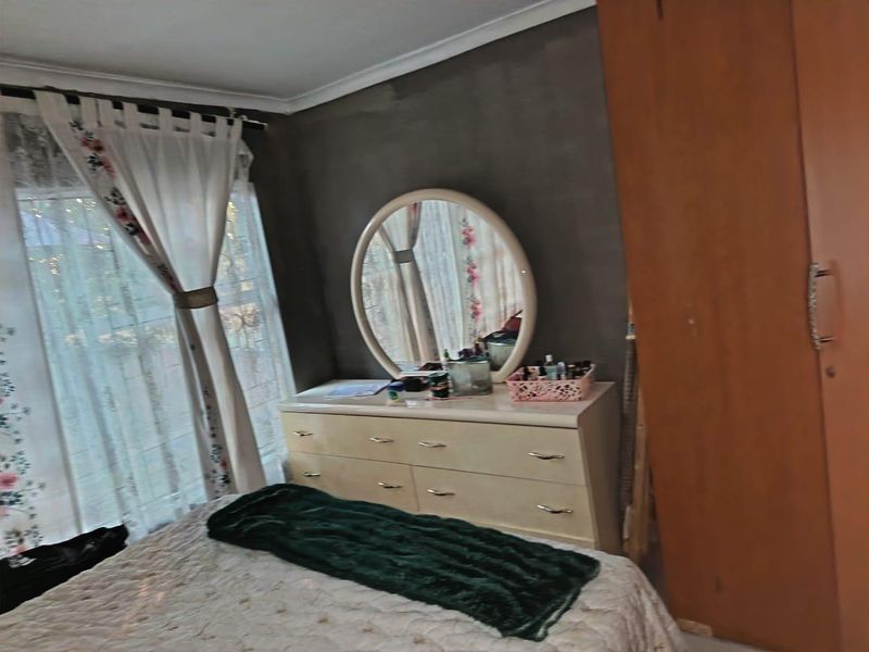 A bedroom featuring a built-in wardrobe and cove cornice, currently requiring cosmetic updates to the wall finishes.