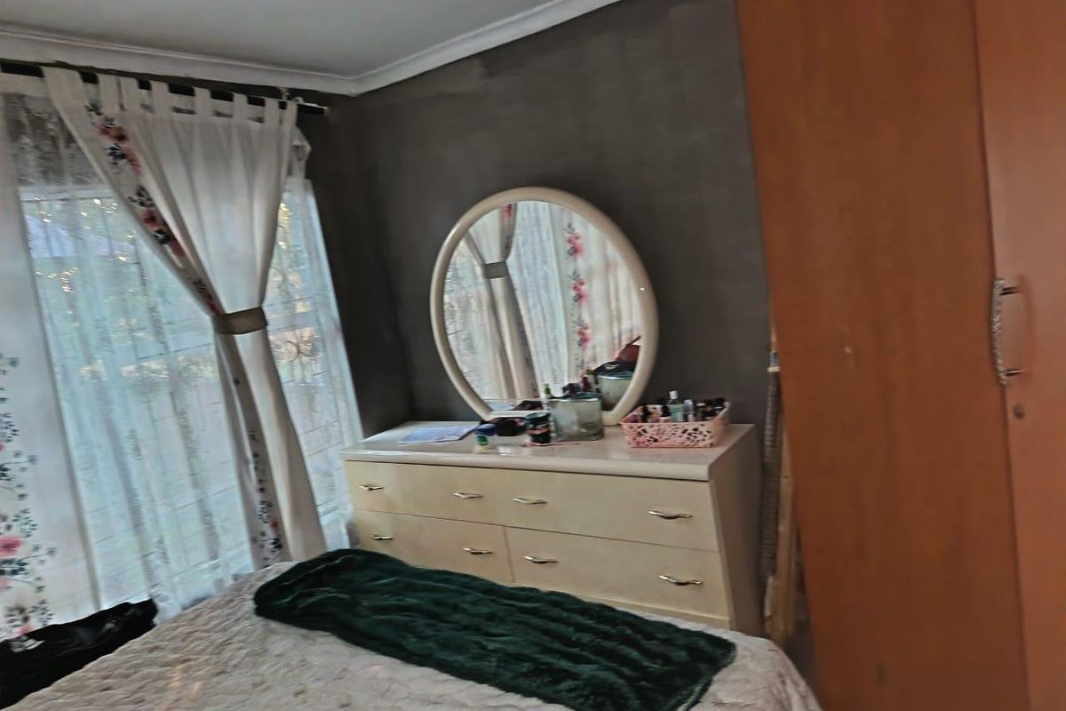 A bedroom featuring a built-in wardrobe and cove cornice, currently requiring cosmetic updates to the wall finishes.