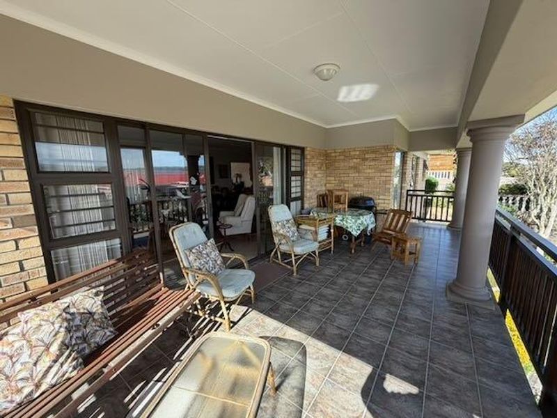 A covered outdoor patio featuring tiled flooring, brick walls, and structural columns, providing access to the interior through large sliding glass doors.