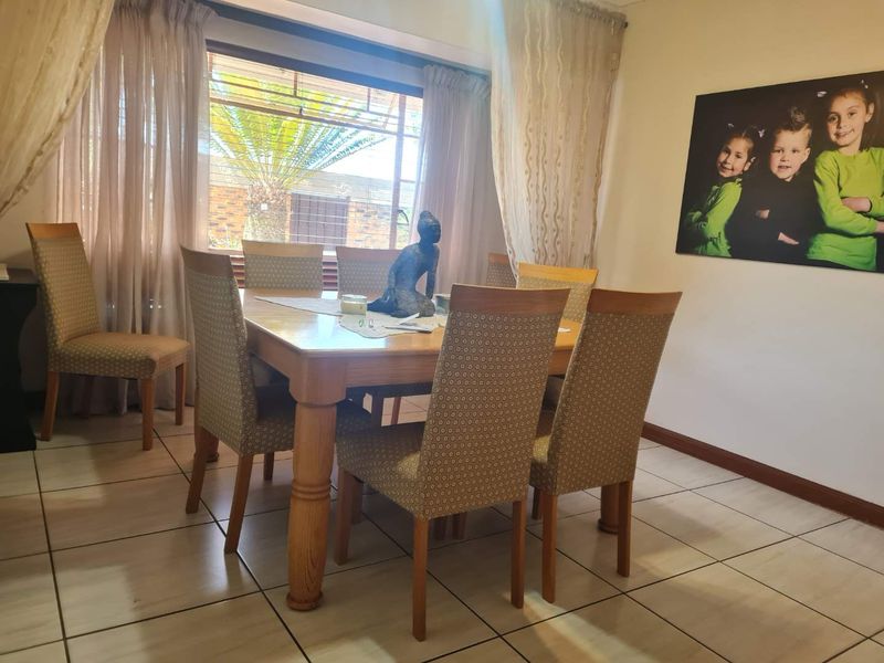 A functional dining room featuring neutral tiled flooring and a large window that provides natural light to the space.