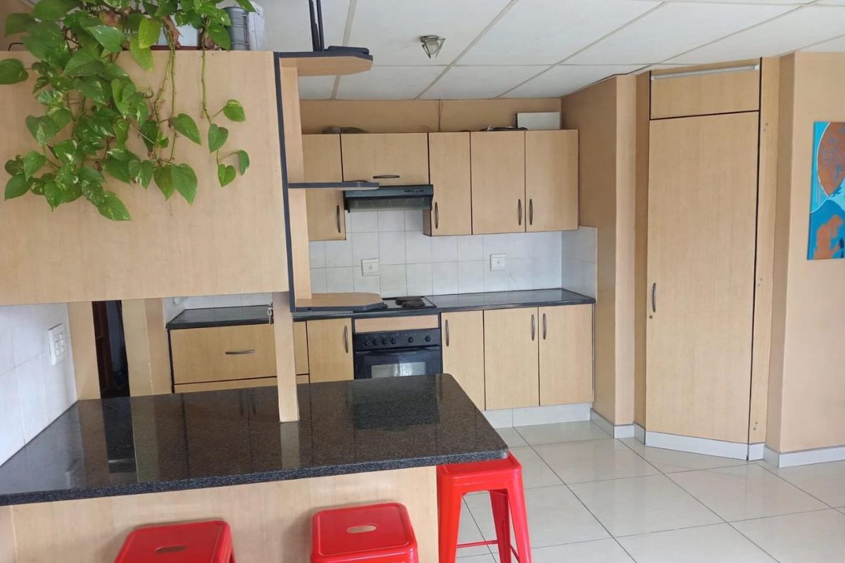 A functional kitchen featuring laminate cabinetry, granite countertops, and built-in appliances with a breakfast bar area and tiled flooring.