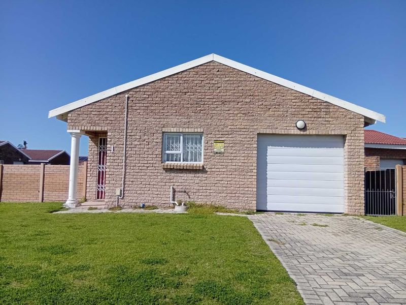 Front elevation of a single-story townhouse featuring a brick facade, single garage, paved driveway, and a small front garden area.