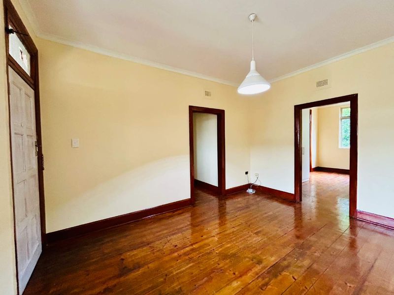 An empty living area featuring polished hardwood floors, classic timber door frames, and neutral wall tones, offering a blank canvas for interior design.