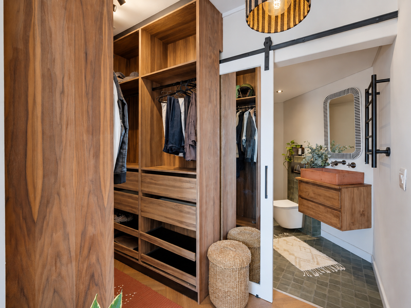 Modern bedroom featuring custom built-in wooden cabinetry and a sliding barn door leading to an en-suite bathroom with high-end fixtures.