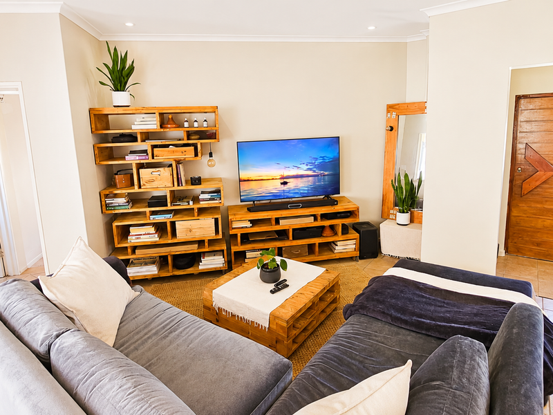 A comfortable living room featuring tiled flooring, recessed lighting, and a solid timber entrance door.