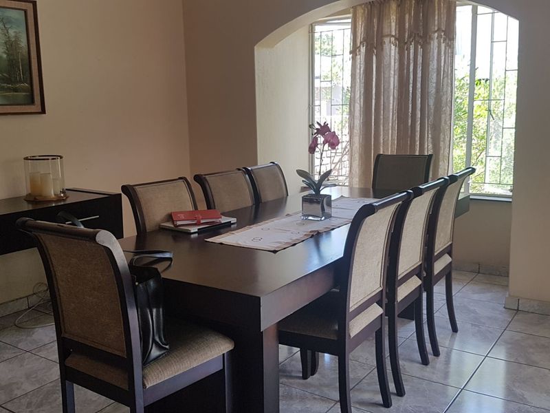 A dining room featuring tiled flooring and an arched window with security bars, providing natural light to the space.