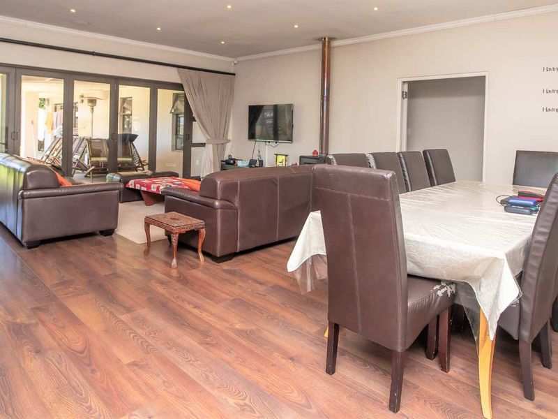 Spacious open-plan living and dining area featuring laminate flooring, recessed lighting, and large sliding glass doors providing seamless access to the outdoor patio.