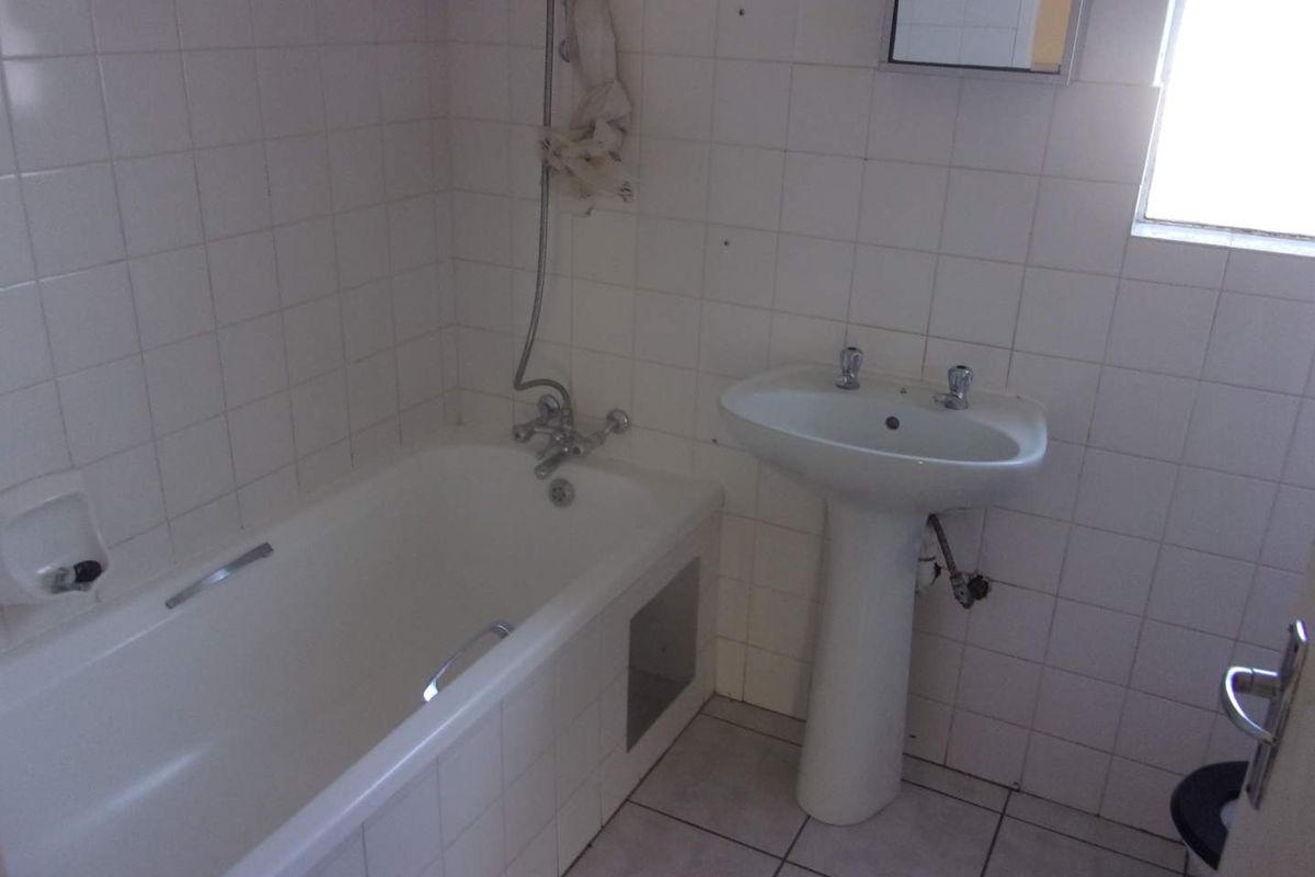 A dated bathroom featuring a standard bathtub, pedestal basin, and tiled finishes, offering a blank canvas for a modern renovation.