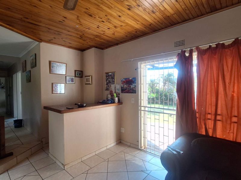 Living area featuring a built-in bar counter, timber ceiling, and tiled flooring with direct access to the garden through a security gate.