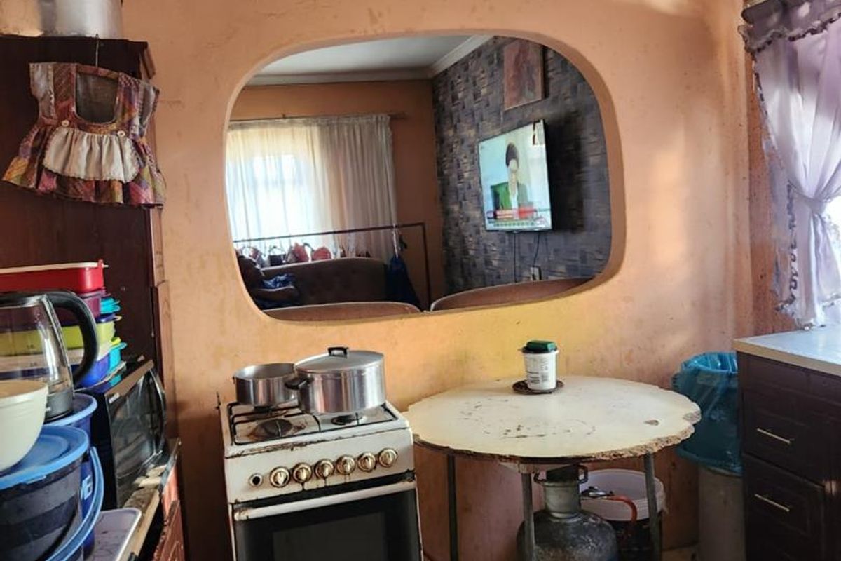 A dated kitchen area featuring a built-in wall opening, tiled flooring, and a freestanding gas stove.