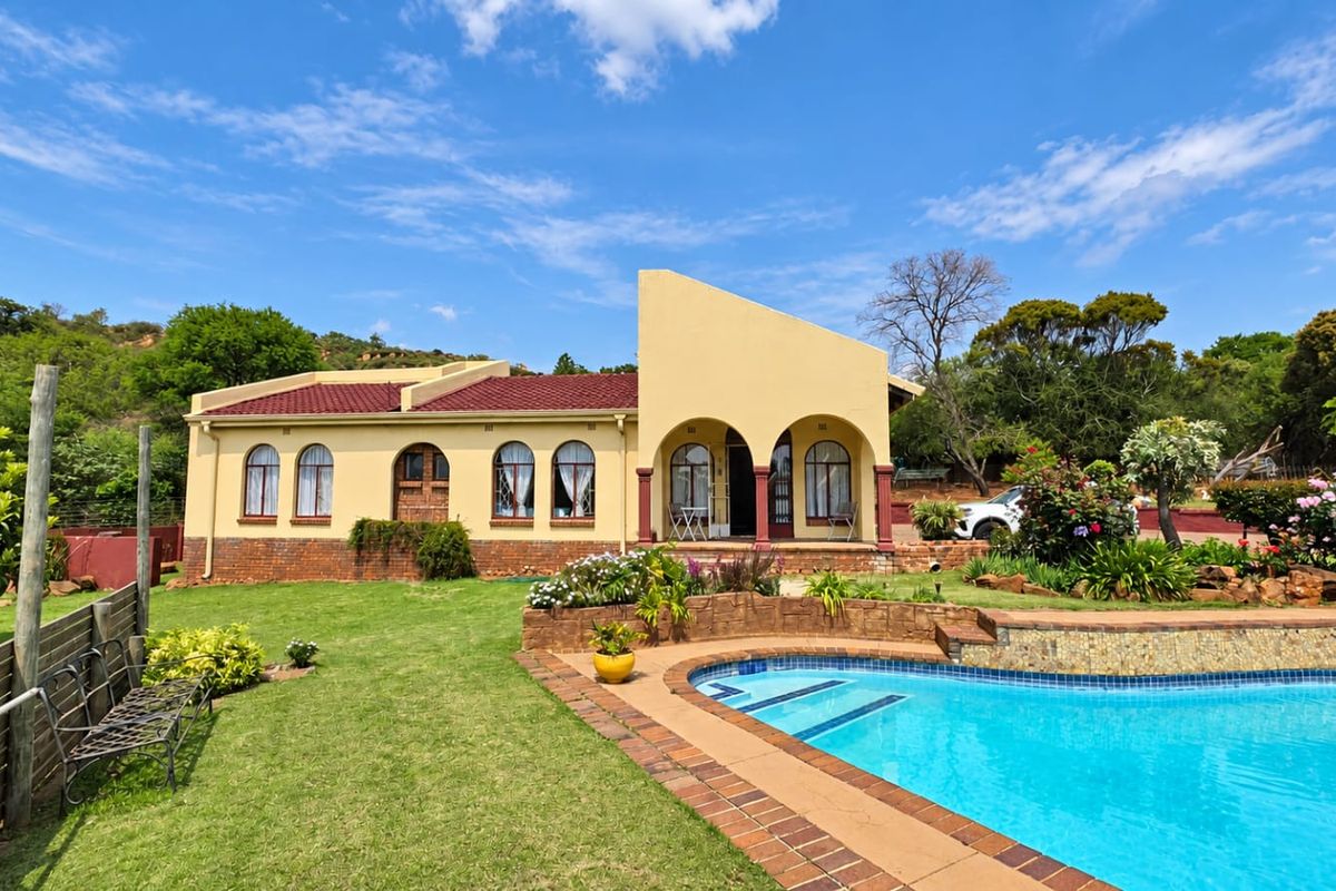 Rear view of the house featuring a swimming pool, landscaped garden, and a covered patio area with arched architectural details.