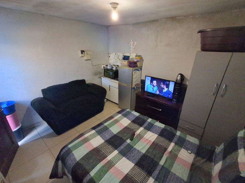 A compact bedroom featuring tiled flooring and basic built-in cabinetry, currently showing signs of wear and requiring cosmetic updates to the wall finishes.